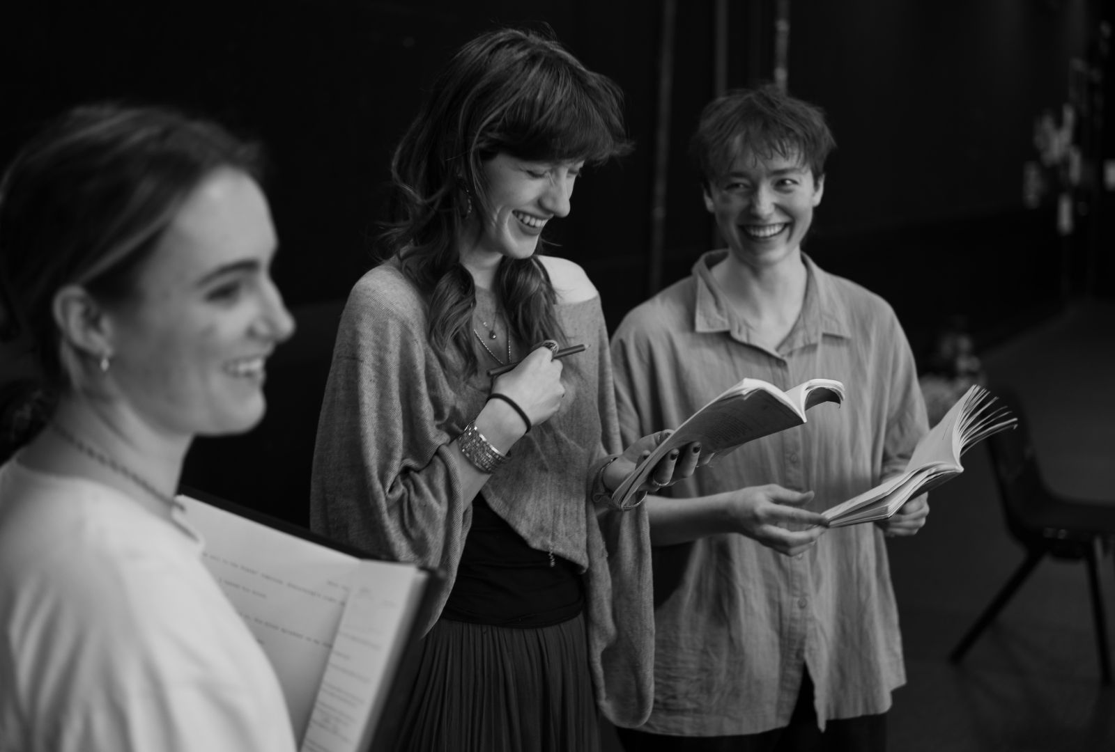 Three people reading scripts smiling.