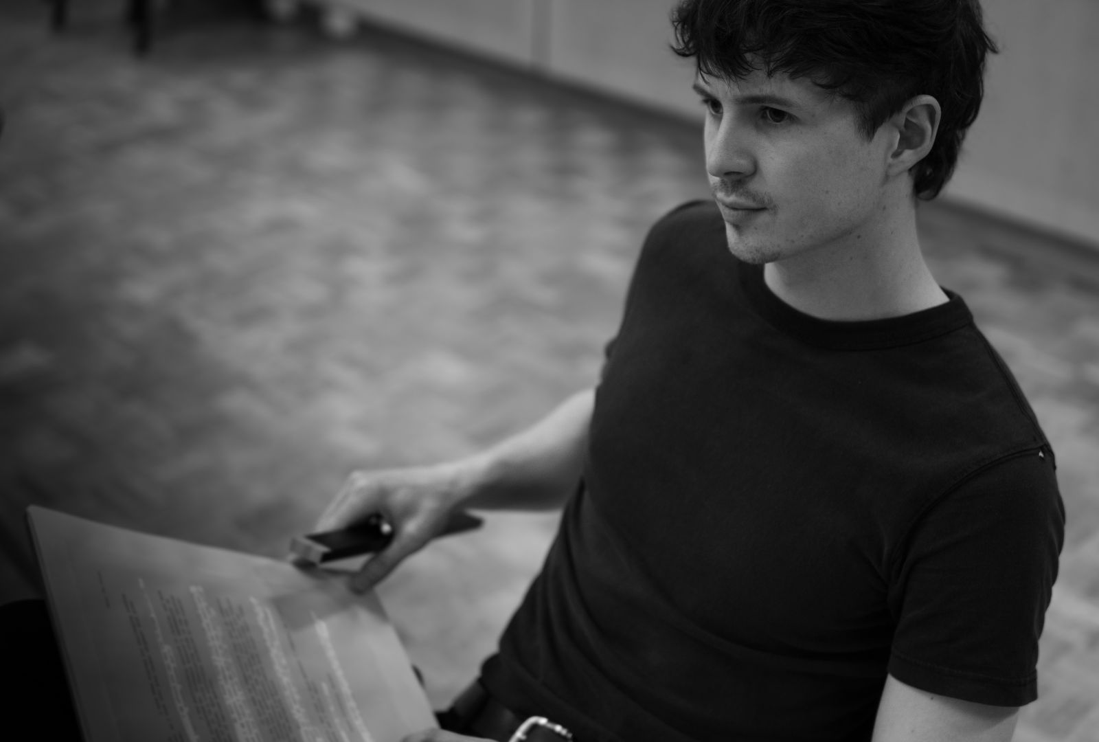 A man in a black shirt reads a script.