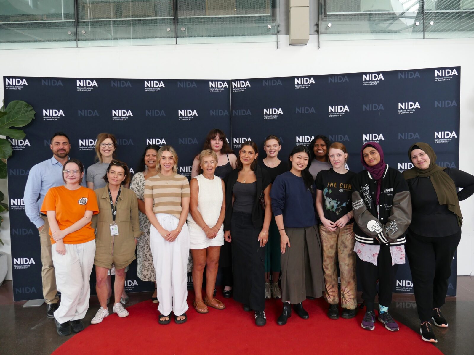 NIDA staff, Netflix representatives and NIDA Open students standing in front of a NIDA branded board in the foyer.