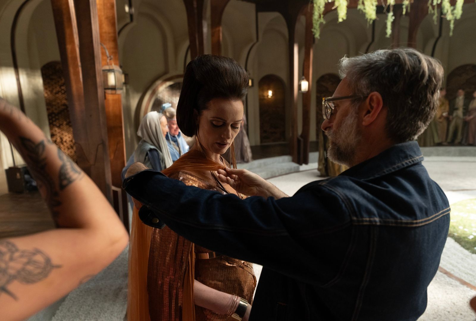 A designer on set adjusting the costume of an actor in fantasy attire. 