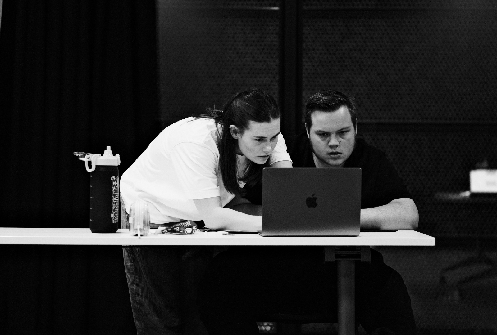 Black and white photo of two people looking at a laptop.