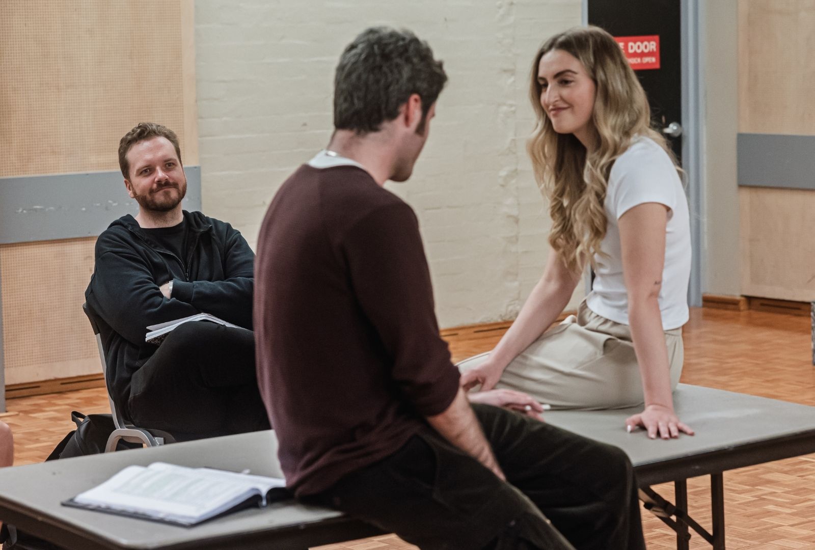 Three people in a rehearsal room sitting on furniture. 