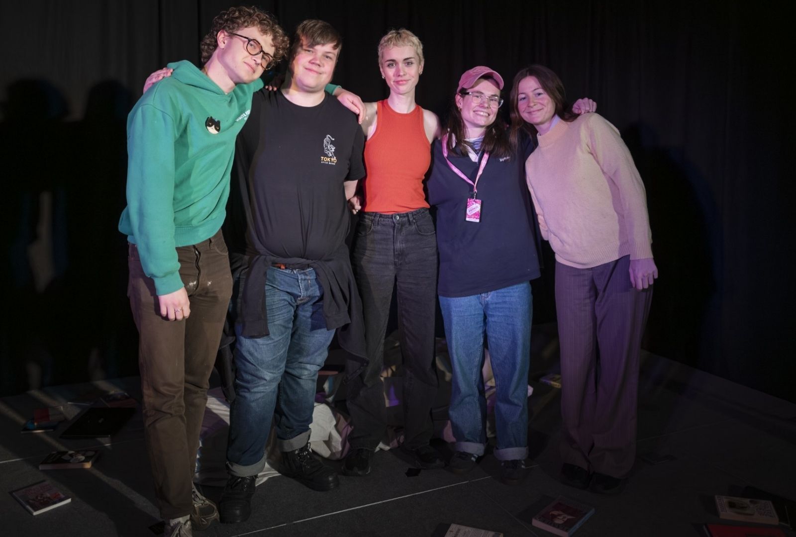 The cast and crew of a show with their arms around each other.