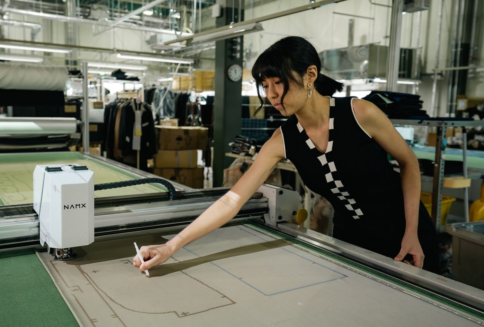 A person drawing patterns in a factory on a suit cutting machine.