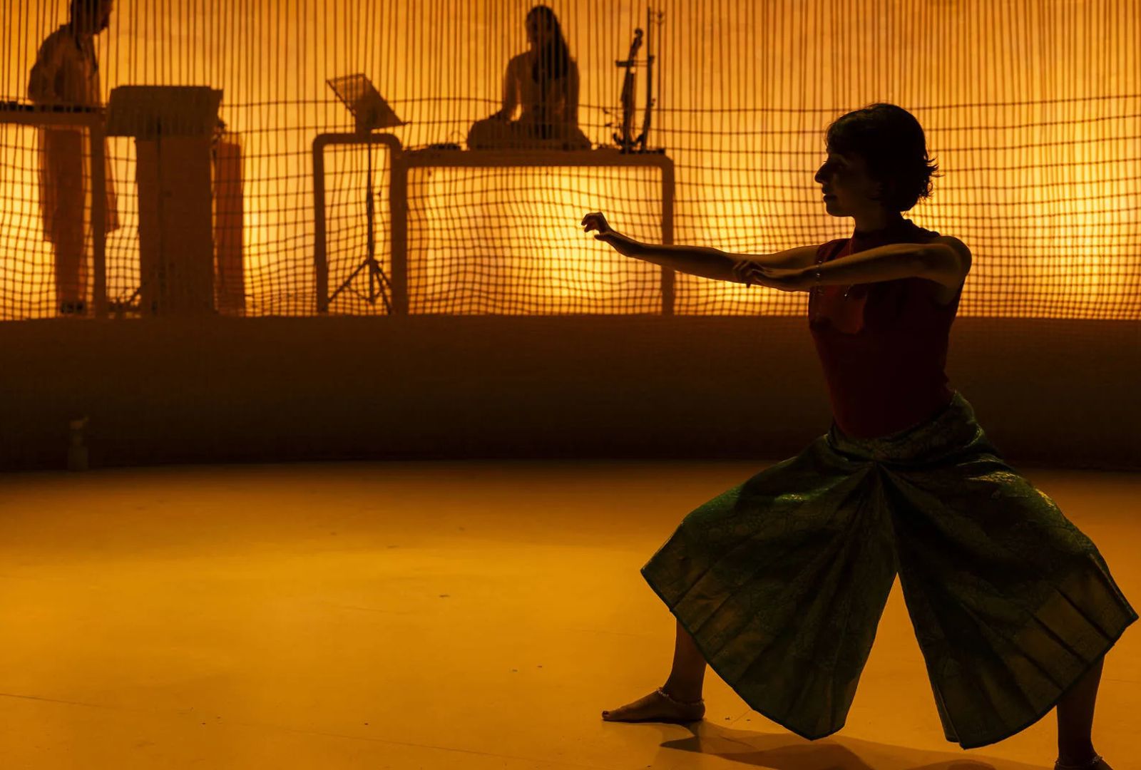 A woman in gold lighting dancing on stage.