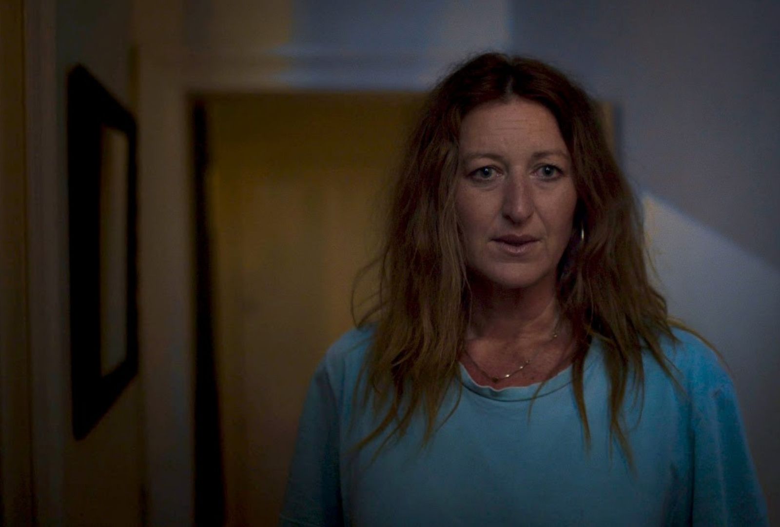 A woman in a hallway looking concerned. 