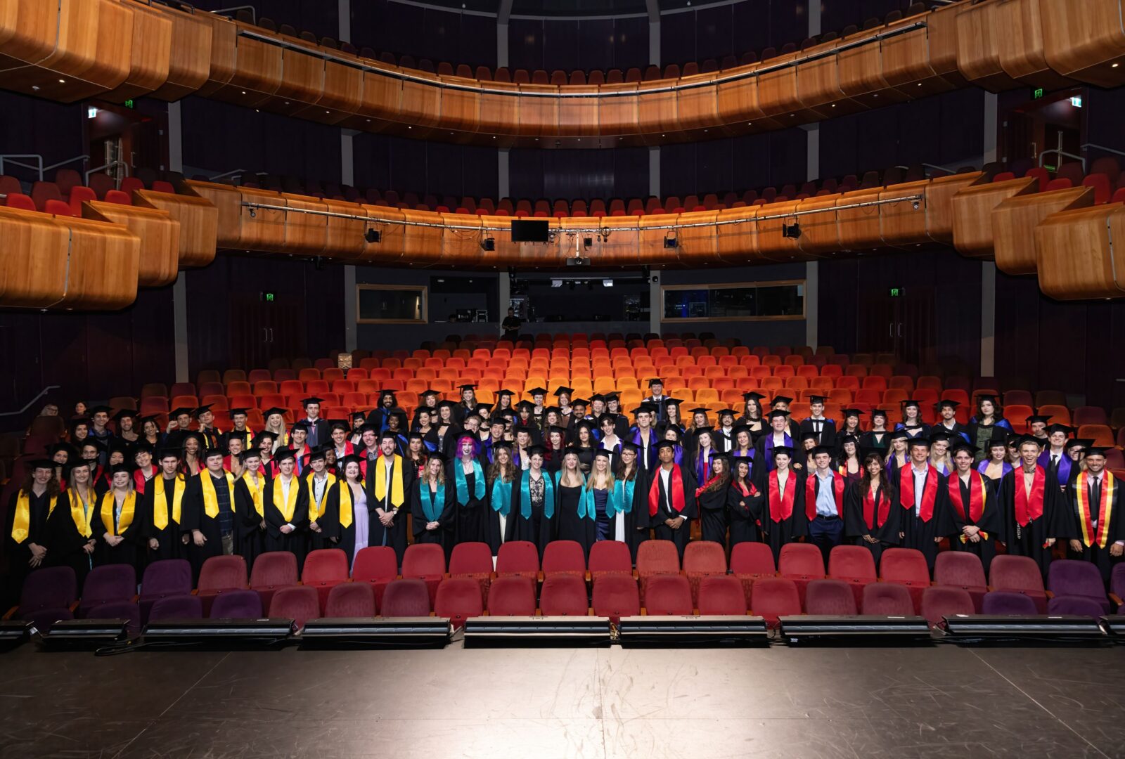 NIDA graduates in the Parade Theatre at NIDA standing in the seated area in their graduate robes.