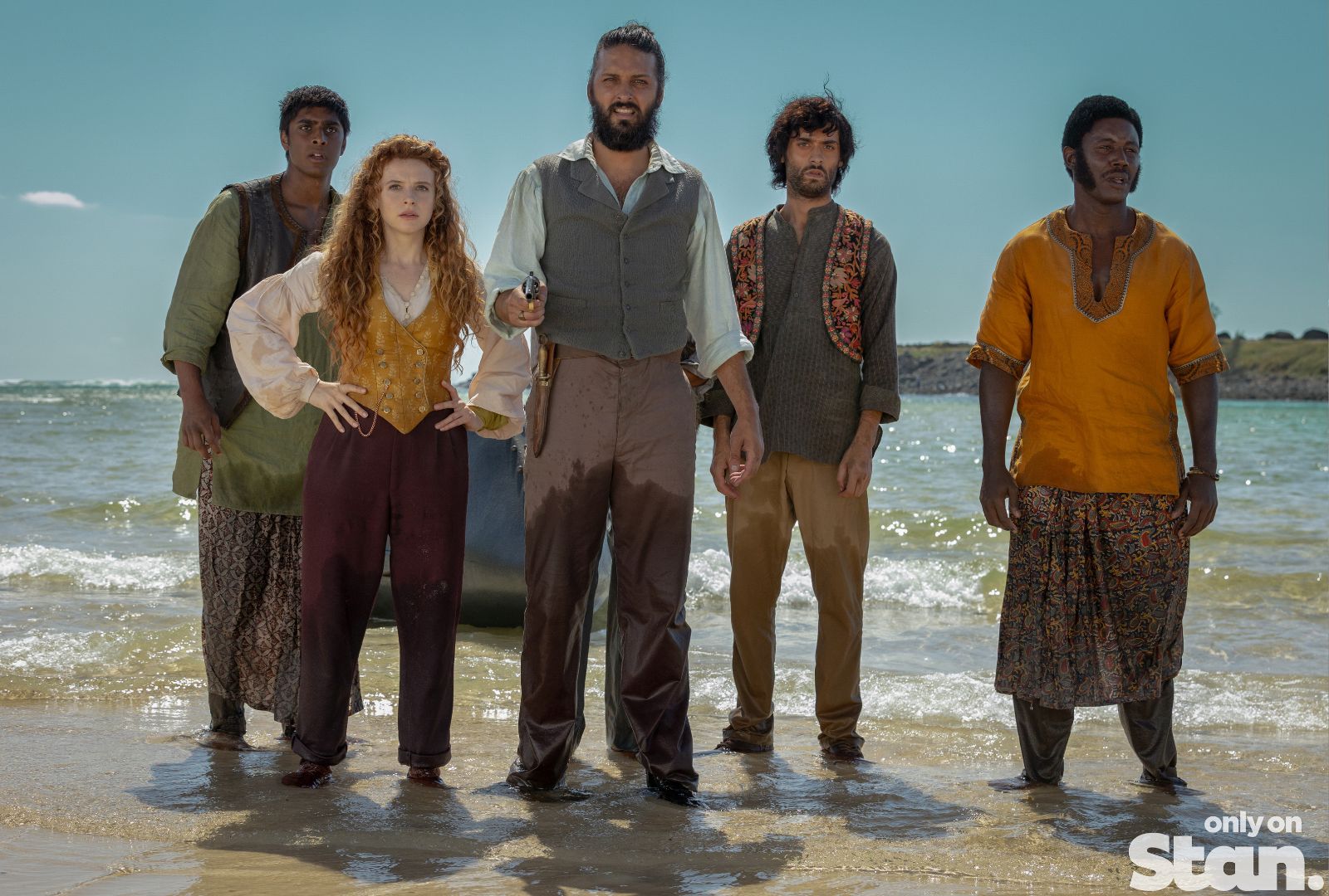 Cast of Nautilus standing in the water on a beach looking concerned.