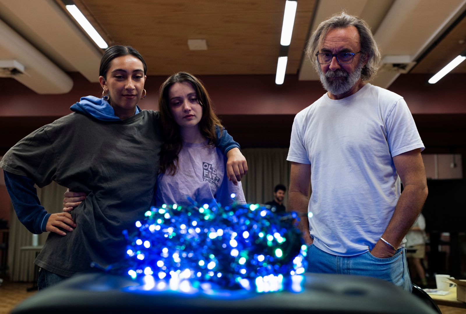From left to right: Lilian Alejandra Valverde, Claudia Elbourne and James Lugton stand in front of a knot of Christmas lights.