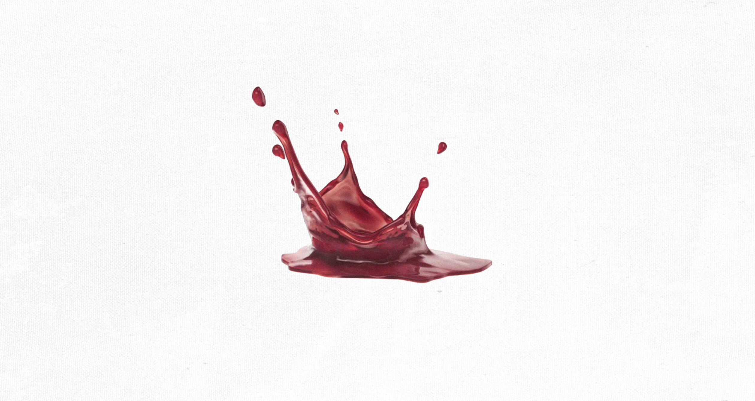 A splash of red liquid captured mid-air against a plain white background, forming dynamic droplets and arcs.