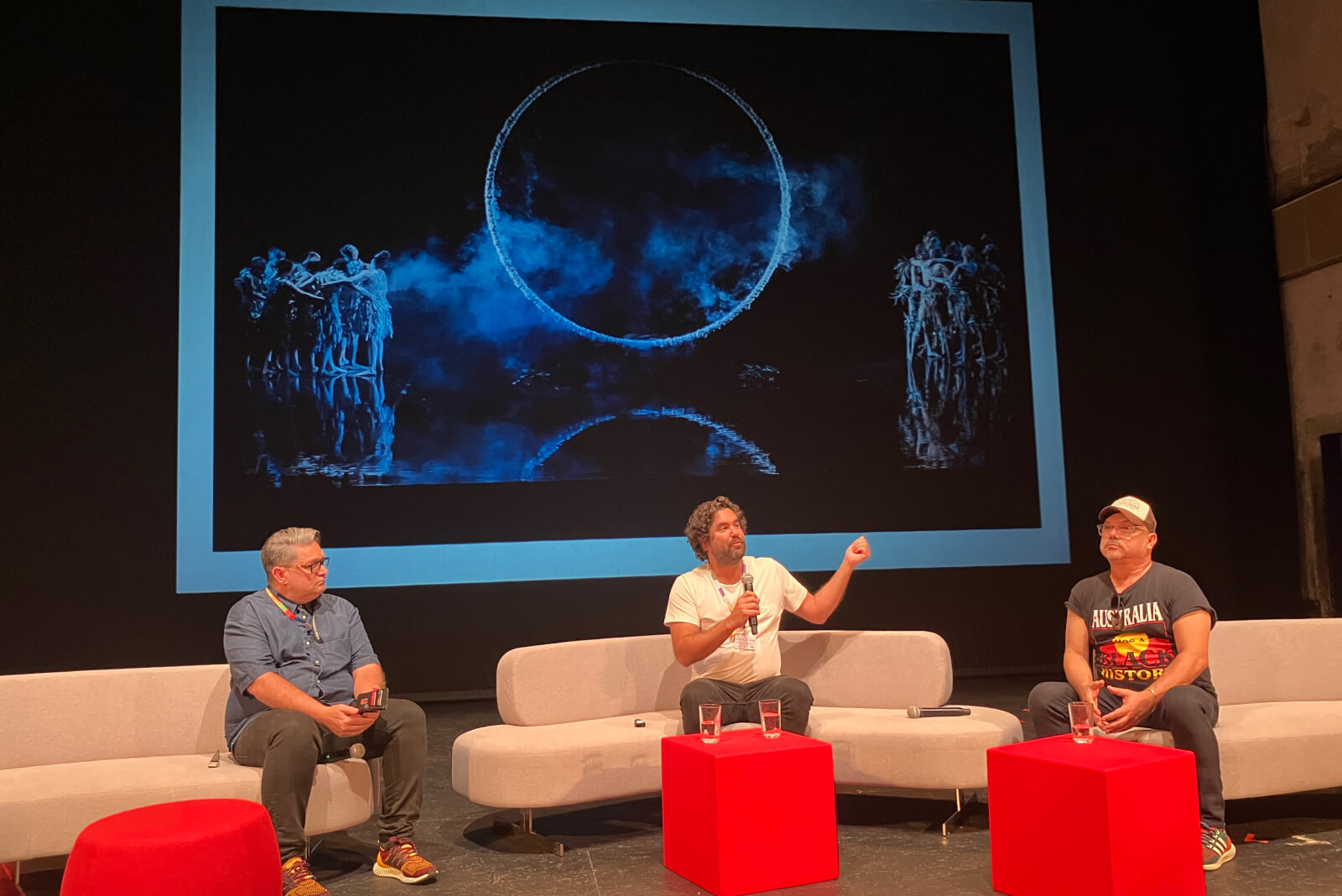 Jacob Nash, Wesley Enoch and Stephen Page in the panel discussion Local Global perspectives on Indigenous Materialities of Performance. The image shown on the screen was of the circular structure from Bangarra's production of Bennelong (2017) that formed a key part of the Australian exhibit.